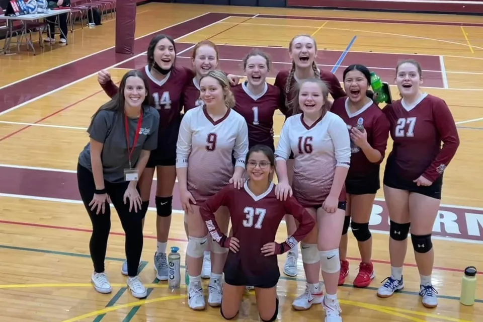 A volleyball team and coaches together in a gym, from the club’s photo archive